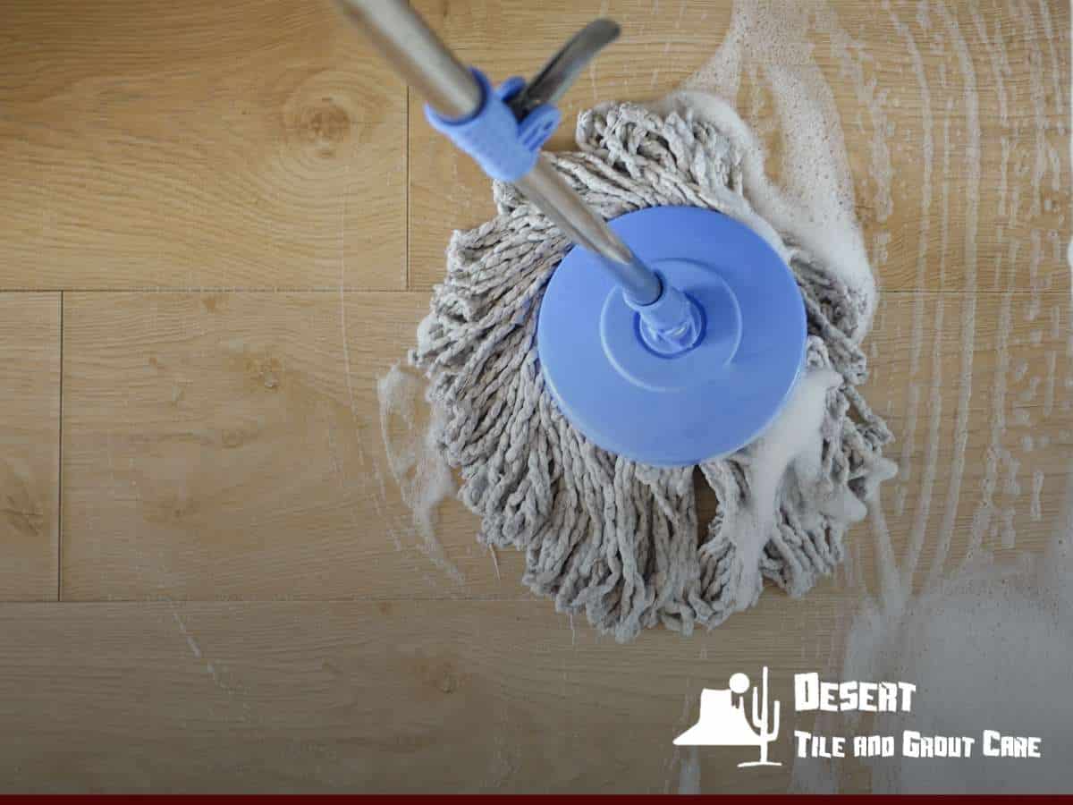 Mop scrubbing a wooden floor with soapy water during Commercial Floor Cleaning by Desert Tile and Grout Care